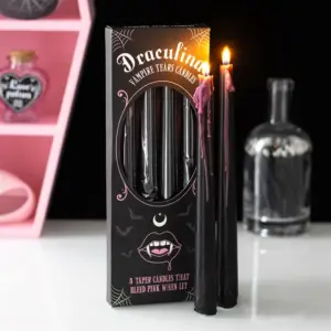 Velas cónicas rosas Lágrimas de vampiro con caja y una vela encendida en una escena gótica