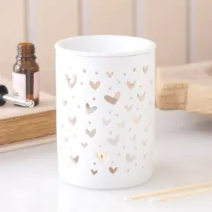 Quemador de aceite y cera con corazones encendido en una escena decorativa