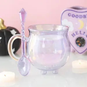 Taza caldero de cristal morado con la cucharilla en una escena mística