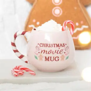Taza rosa con motivos navideños con bebida caliente en una escena navideña