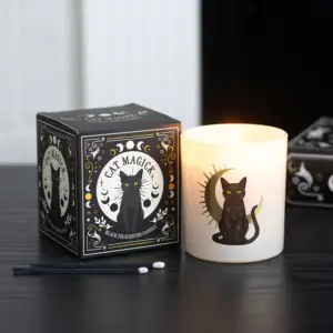 Vela de higo negro Black Cat Magick encendida junto a su caja en una escena gótica